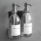 Clear glass soap dispenser bottle set on metal wall mounted bracket for hand soap and hand cream for hotels, home, spas, cafe, restaurant, b&b